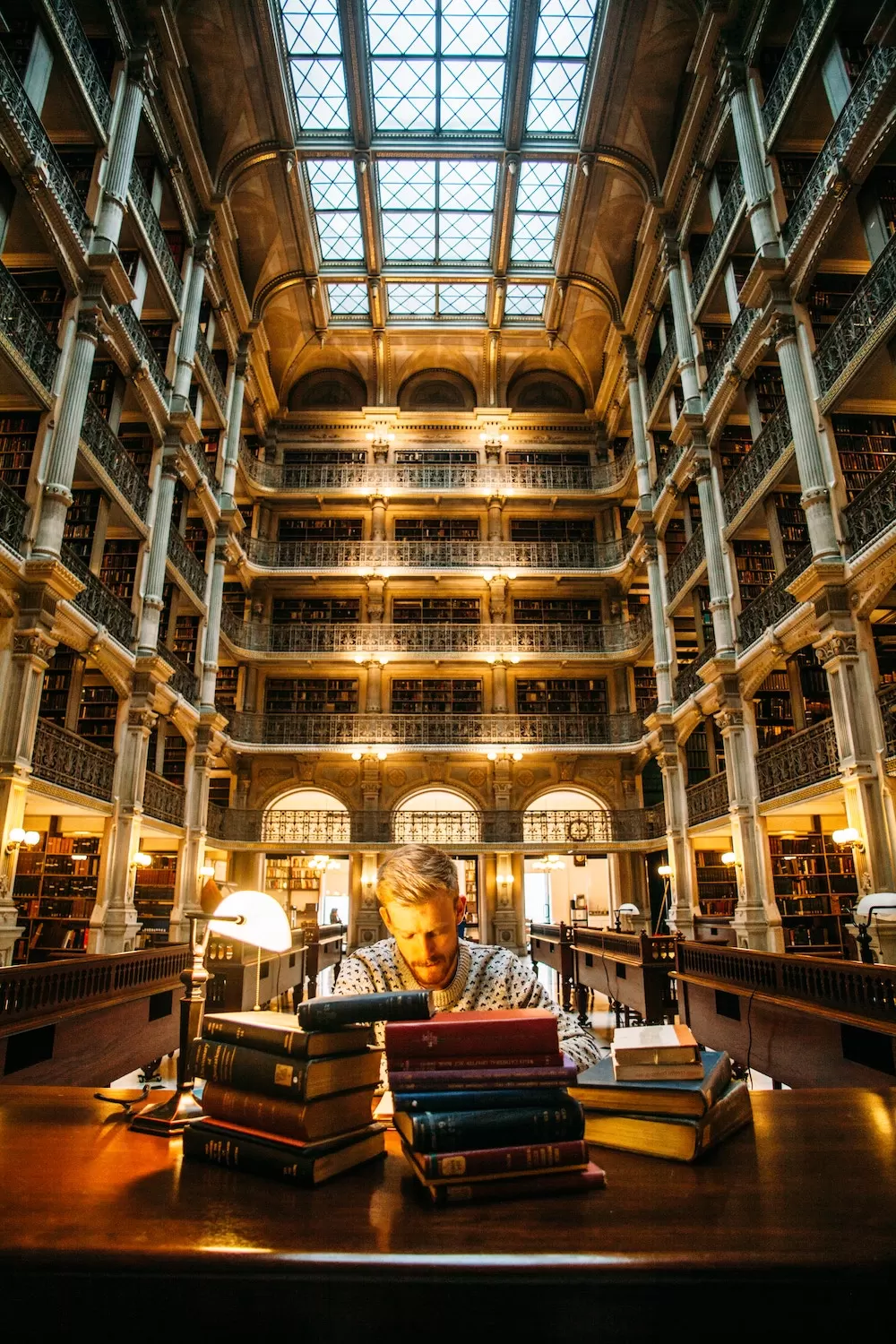 hombre rodeado de libros en una biblioteca
